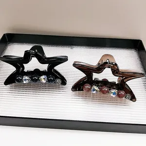 Dettaglio delle mollette a forma di stella con strass nei colori nero e ambra