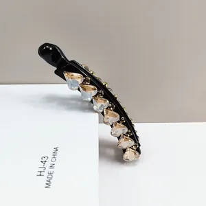 Detail shot of heart-shaped champagne crystals on a black resin banana hair clip