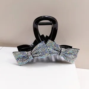Macro shot of elegant black shark clip with shimmering rhinestone bow and glossy finish