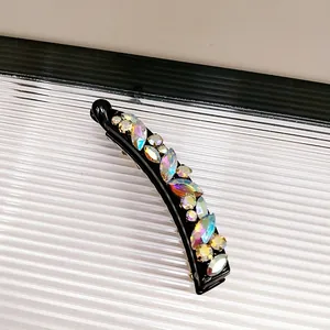 Detailansicht der irisierenden Kristalle auf einer gebogenen schwarzen Bananen-Haarspange