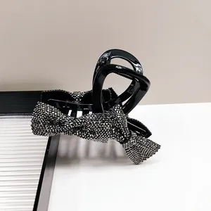 Detail of elegant black hair claw clip featuring a double bow with shimmering silver rhinestones