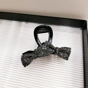 Close-up of black hair claw clip featuring a rhinestone bow with shimmering crystals