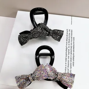 Detail of two bow hair claws with sparkling rhinestones in black and iridescent finishes