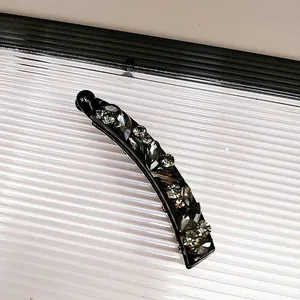 Detail einer schwarzen Bananenspange mit dunkelgrauen Kristallverzierungen