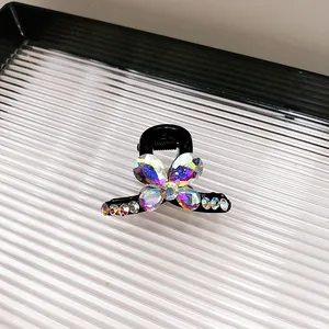 Détail d'une petite pince à cheveux noire avec des pétales de cristal colorés
