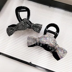 Detail showing bow-shaped hair claw clips with sparkling rhinestones in black and AB colors