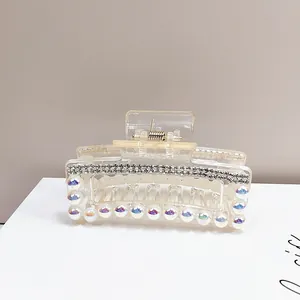 Dettaglio della pinza per capelli in acrilico con strass argentati e perle iridescenti