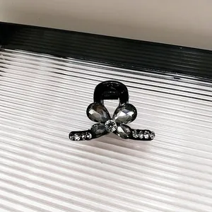 Vue détaillée de la petite pince à cheveux noire avec un élégant papillon en cristal gris