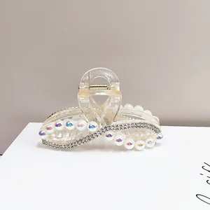 Dettaglio delle catene di strass e perle sulla pinza per capelli in resina champagne