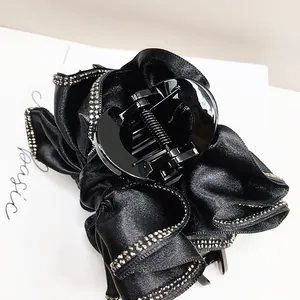 Détail d'une pince à cheveux en satin noir ornée de strass argentés étincelants