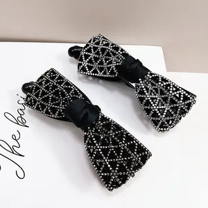 Détail de barrettes bananes à nœud noir ornées de strass en cristal étincelants