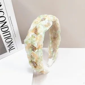 Detailed close-up of woven floral headband with yellow fabric and pearl accents
