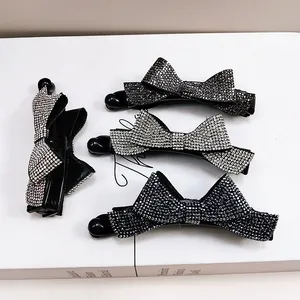 Détail de quatre élégantes barrettes à nœuds avec des strass étincelants en gris et noir