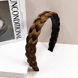 Détail du serre-tête tressé large avec texture satinée sur un support minimaliste