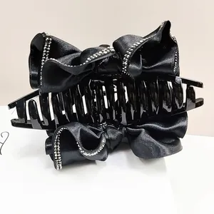 Détail d'une pince à cheveux avec nœud en satin noir et double rangée de strass brillants
