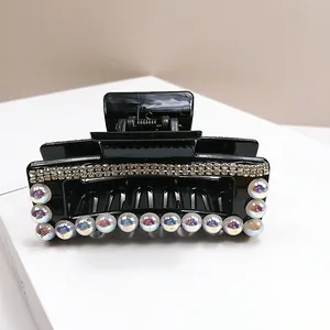 Macro di una molletta per capelli nera con strass scintillanti e perle iridescenti