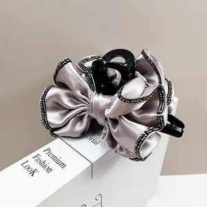 Détail d'une pince à cheveux en satin gris avec strass noirs sur fond de livre chic