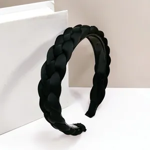 Détail d'un serre-tête tressé en satin noir avec dents antidérapantes et texture tissée