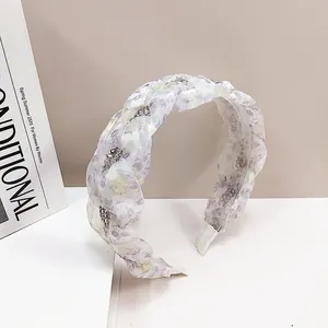 Detailed macro of floral fabric braided headband with sparkling crystals and non-slip teeth