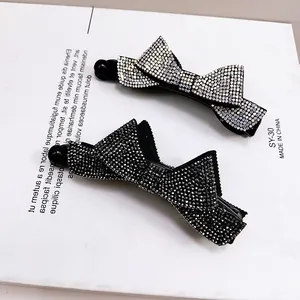 Détail macro des pinces à cheveux banane avec nœud en strass noir et argent