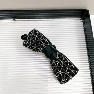 Détail de la pince banane avec nœud en cristaux et ruban en satin noir au centre