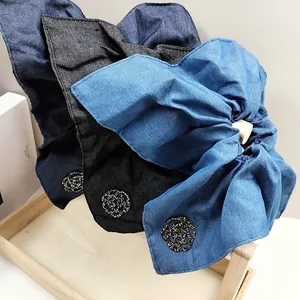Detail of denim bow hair scrunchies with camellia floral embellishments and texture
