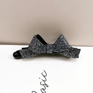 Détail de la pince banane nœud noir ornée de strass argentés étincelants sur base brillante