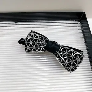 Détail d'une pince à cheveux à nœud en strass avec un centre en ruban de satin noir