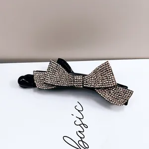 Détails d'une pince à cheveux banane élégante avec nœuds en strass champagne scintillants