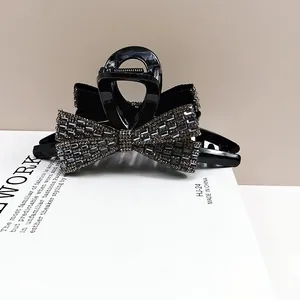 Elegant black bow hair claw clip with sparkling rhinestones for sophisticated styling