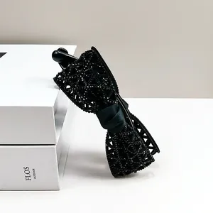 Gros plan sur la pince banane noeud en résille noire ornée de strass et noeud textile