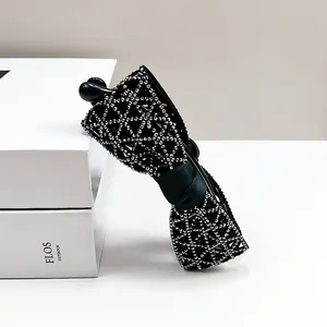 Pince banane élégante en forme de nœud noir avec strass argentés sur boîte blanche