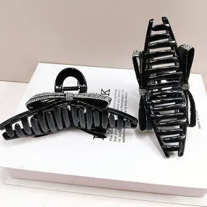 Detail of two black bow hair claws with sparkling rhinestones on a white book prop