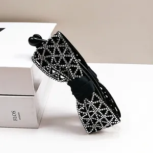 Détail des strass argentés brillants sur une pince banane noire avec élégant nœud en tissu