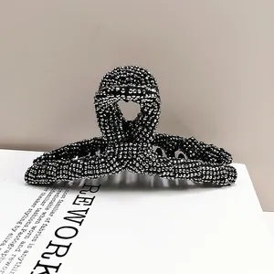 Detailed view of elegant large hair claw clip with silver rhinestones on black base