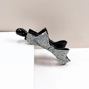 Vue détaillée des strass blancs superposés sur une pince à cheveux banane noire
