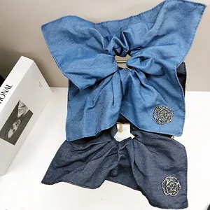 Close-up of denim bow scrunchie featuring a silver camellia rhinestone ornament