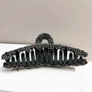 Close-up of elegant black shark hair claw clip with shimmering rhinestones and teeth detail