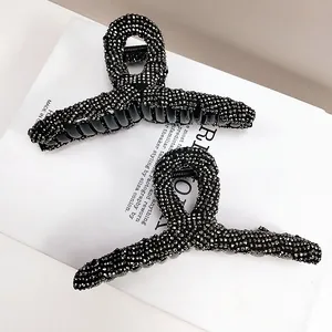 Detail view of two black rhinestone shark hair clips with sparkling crystals on white magazine