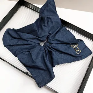 Dettaglio dell'elastico in denim blu navy con fiocco di strass dorati e trama a saia