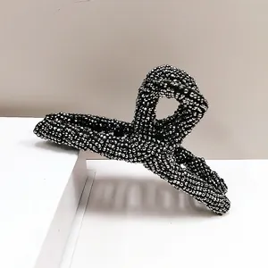Elegant large shark hair claw clip with pavé rhinestones on a white minimalist background