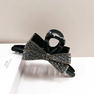 Macro shot of sparkling bow shark hair clip with grey rhinestones on black resin