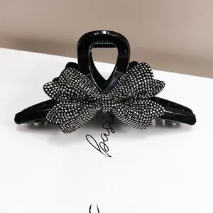 Dettaglio di un fermaglio per capelli nero con fiocco di strass su uno sfondo bianco