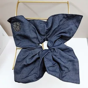 Close-up of denim scrunchie with camellia rhinestone ornament on a golden stand