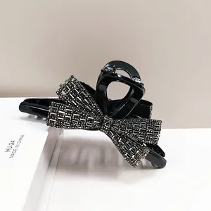 Detailed macro view of a glossy black bow hair claw clip with shimmering rhinestones