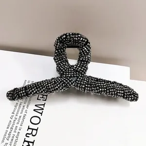 Macro shot of large silver shark hair claw clip with full rhinestone inlay on white magazine
