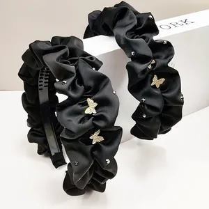 Détail d'un serre-tête en satin plissé noir avec papillons en strass et dents antidérapantes