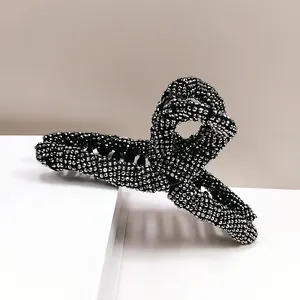 Close-up of a large black hair claw clip fully encrusted with sparkling rhinestones