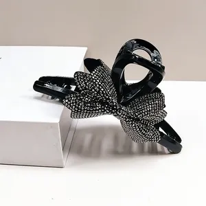 Dettaglio di un fermaglio per capelli nero con un grande fiocco ricoperto di strass