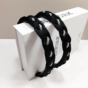 Dettaglio del cerchietto in raso nero intrecciato con strass argentati lucidi